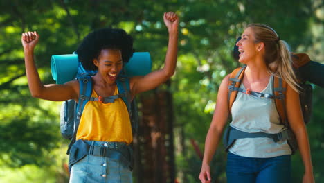 Two-Female-Friends-With-Backpacks-Setting-Off-On-Vacation-Hiking-Through-Countryside-Together