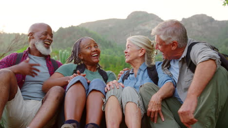 Aktive-ältere-Freunde-Sitzen-Zusammen-Und-Machen-Eine-Pause-Beim-Wandern-Durch-Die-Landschaft