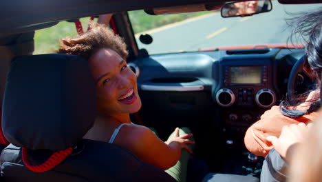 Portrait-Of-Laughing-Female-Friends-Having-Fun-In-Open-Top-Car-On-Road-Trip