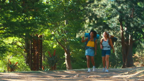 Two-Female-Friends-With-Backpacks-Giving-Each-Other-High-Five-As-They-Set-Off-On-Hiking-Vacation