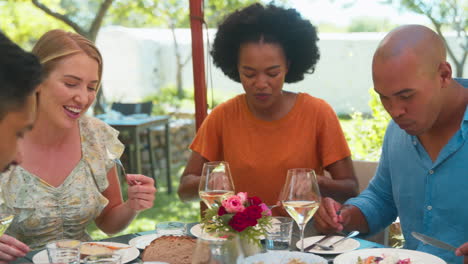 Group-Of-Friends-Enjoying-Outdoor-Meal-And-Wine-On-Visit-To-Vineyard-Restaurant