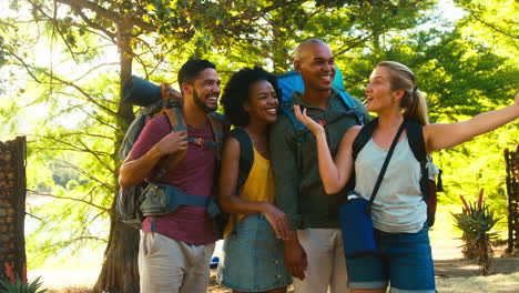 Group-Of-Friends-With-Backpacks-Making-Video-Call-On-Mobile-Phone-Whilst-Hiking-In-Countryside