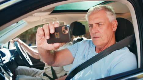 Passagier-Fotografiert-Mit-Mobiltelefon,-Während-älteres-Paar-Einen-Tagesausflug-Im-Auto-Genießt