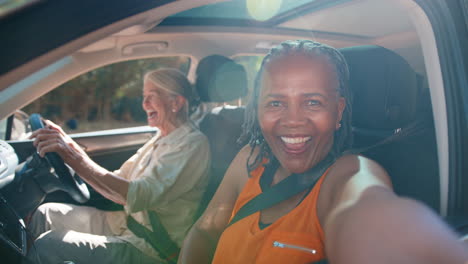 Passagier-Macht-Selfie-Mit-Dem-Handy,-Während-Zwei-ältere-Freundinnen-Einen-Tagesausflug-Im-Auto-Genießen