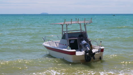 Rocking-over-the-soft,-foamy-waves,-a-speed-boat-anchored-in-the-shallow-waters-of-Pattaya-Beach-in-Chonburi-province,-Thailand