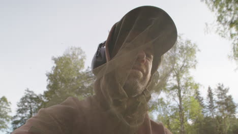 Man-outdoors-in-summer-wearing-mosquito-head-net-against-swarming-mosquitoes