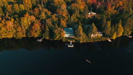 static-drone-shot-over-canadian-lake-during-fall-season-with-canoe-approching-the-pontoon