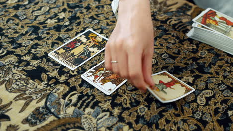 A-woman-giving-a-tarot-reading-with-the-tower-the-five-of-pentacles-and-the-hanged-man-cards