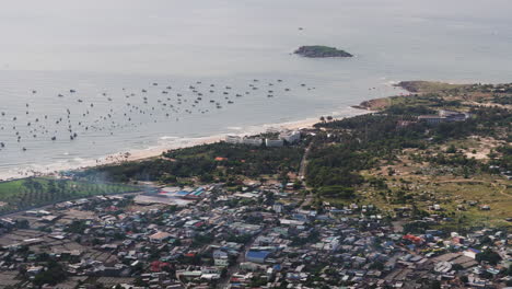 Coastline-with-boats-and-Hon-Lao-island-in-Mui-Ne,-aerial-view