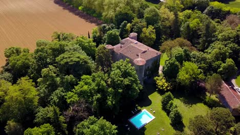 Aerial-view-of-medieval-castle-nestled-in-trees-near-vast-agriculture-farm