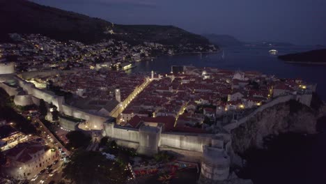 Coratia-Aerial:-Dubrovnik-at-dusk,-glowing-streets,-and-Adriatic-Sea