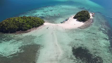 Aerial-reveal-of-tourists-crossing-famous-sandbar-at-Tup-Island,-Krabi