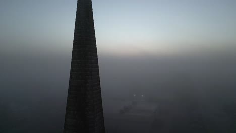 An-aerial-view-of-a-brick-church-in-the-foreground,-surrounded-by-fog-during-a-golden-sunrise-on-Long-Island,-New-York