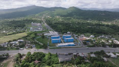 Aerial-view-of-traffic-on-highway-in-front-of-prison-and-green-mountains-in-Background