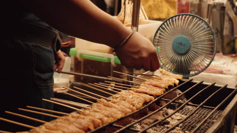 Grillen-Sie-Hähnchensatay-über-Holzkohle-Und-Würzen-Sie-Streetfood-In-Bangkok,-Thailand-Bei-Nacht