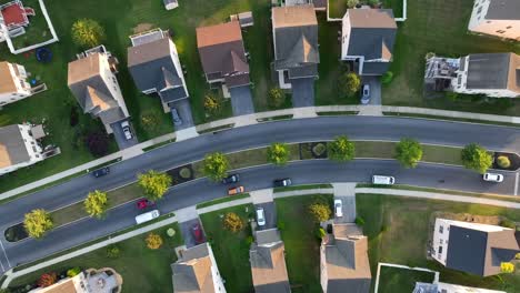 Top-down-aerial-shot-of-cars-driving-through-American-neighborhood-of-townhouses