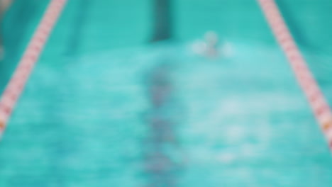 Blurred-out-of-focus-shot-of-professional-swimmer-athlete-swimming-in-pool