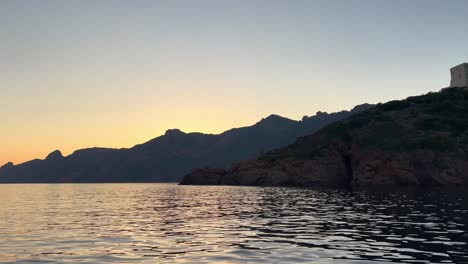 Girolata-castle-at-dusk-seen-from-sailing-boat-touring-Corsica-island-in-France