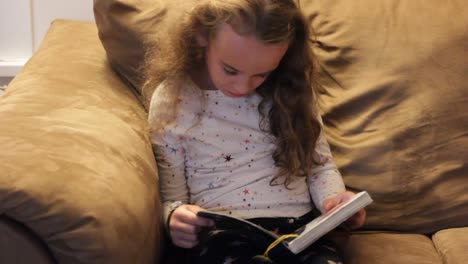 LITTLE-GIRL-READING-A-BOOK-ALONE-ON-THE-COUCH