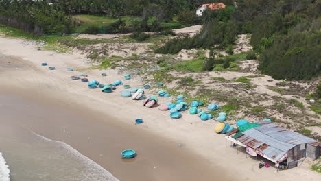 Blue-coracle-boats-on-beach-at-fisherman-camp-in-Mui-Ne,-Vietnam,-aerial-view