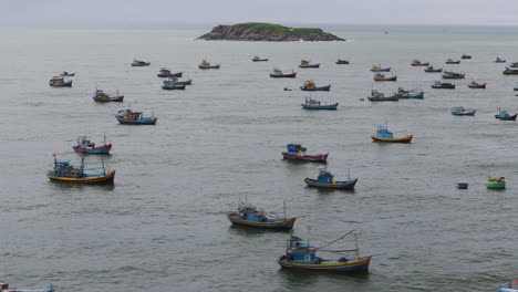 Traditional-Vietnamese-fishing-boats-anchored-offshore-of-Mui-Ne,-aerial-trucking-pan