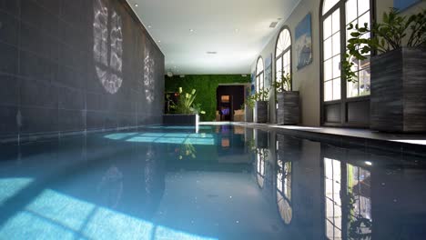 Low-angle-panning-shot-of-indoor-luxurious-swimming-pool-of-a-modern-mansion