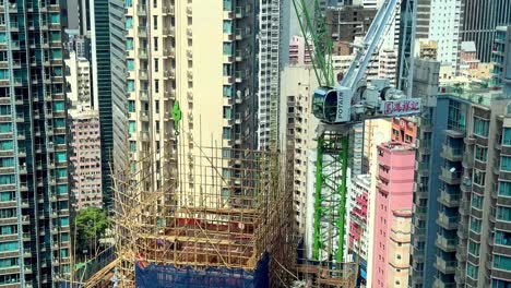 Baustelle-Mit-Bambusgerüsten-Im-Dichten-Stadtbild-Hongkongs-Mit-Umliegenden-Wohnhochhäusern-Und-Turmdrehkran