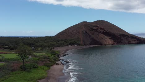 Low-rising-aerial-shot-flying-over-Maluaka-Beach-towards-the-cinder-cone-crater-Pu'u-Olai-in-South-Maui,-Hawai'i