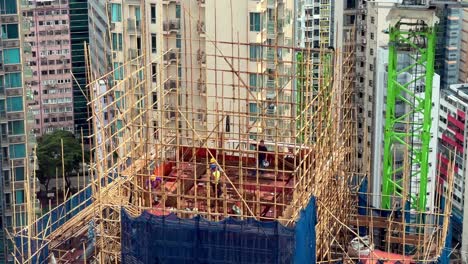 Bauarbeiter-Bauen-Ein-Hochhaus-Mit-Bambusgerüsten-Im-Dichten-Stadtbild-Von-Hongkong