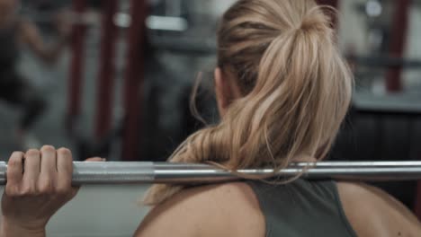 Back-view-of-caucasian-woman-lifting-barbell-in-the-gym.