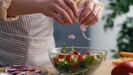 Close-up-of-woman-adding-onions-for-salat-in-the-kitchen.