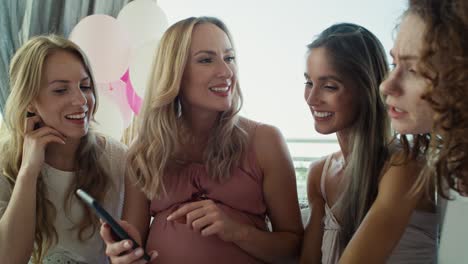 Group-of-adult-women-looking-at-mobile-phone-at-baby-shower.