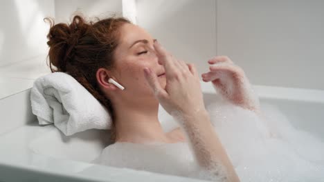 Caucasian-woman-taking-a-bath-and-listening-music.