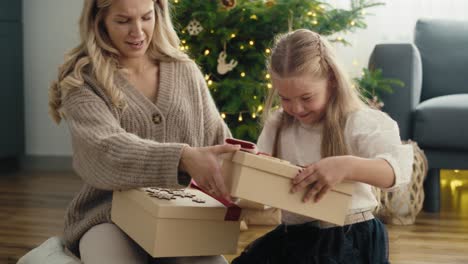 Side-view-of-caucasian-girl-and-mother-giving-and-receiving-Christmas-gifts-and-later-opening-to-check-the-content.