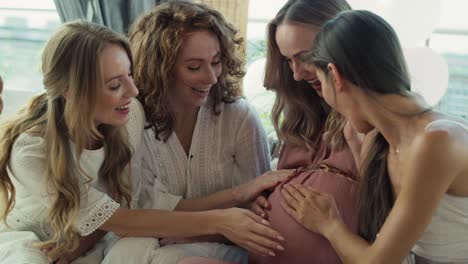 Gruppe-Lächelnder-Erwachsener-Frauen-Bei-Der-Babyparty,-Die-Die-Glocke-Einer-Schwangeren-Frau-Berühren.
