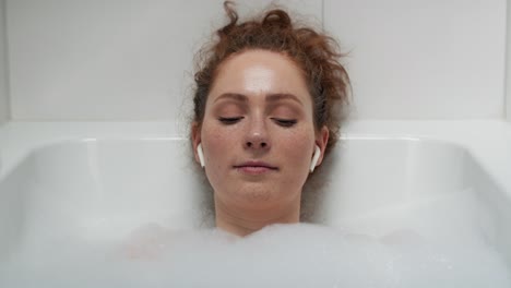 Caucasian-woman-taking-a-bath-and-listening-music.