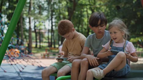Group-friends-using-mobile-phone-at-the-playground-in-summer-day.