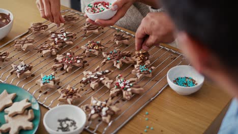 High-angle-view-of-multi-ethnicity-couple-decorating-sweet-cookies-with-colorful-sprinkles-during-the-Christmas.