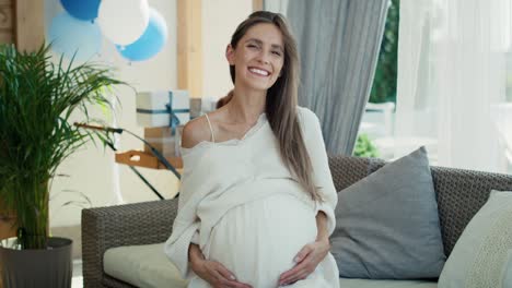Portrait-of-smiling-pregnant-woman-with-blue-decorations-outdoors.