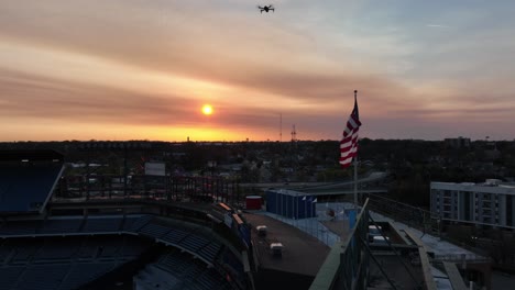 Drone-hovering-over-Center-Parc-Stadium-during-sunset,-Remote-Controller-flying-robot
