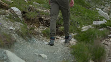 Low-angle-close-up-of-unrecognizable-man-legs-hiking-mountain-trail,-static