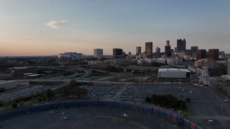 An-aerial-view-of-Hank-Aaron-Wall-in-the-Parking-lot-at-Turner-Field-with-the-view-of-Atlanta-government-buildings,-skyscrapers-in-background-at-sunset,-Traffic-movement-on-the-freeway-in-urban-city