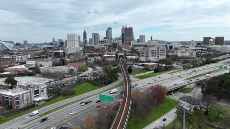 Aerial-timelapse-of-rapid-transit-metro-running-along-Downtown-Atlanta-freeway,-Highway-traffic,-Iconic-Skyscrapers-of-Georgia,-USA