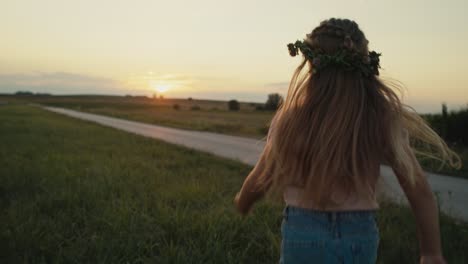 Rear-view-of-little-caucasian-girl-running-toward-the-sunset-on-meadow.