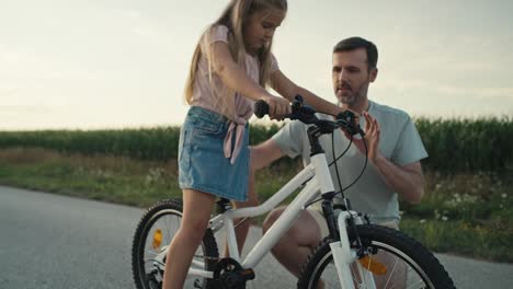 Padre-Caucásico-Enseñando-A-Su-Pequeña-Hija-A-Andar-En-Bicicleta.