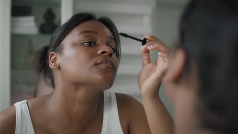 Afroamerikanische-Frau,-Die-Im-Spiegelbild-Wimpern-Anwendet