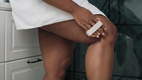 African-American-woman-doing-peeling-of-her-legs-in-the-domestic-bathroom.