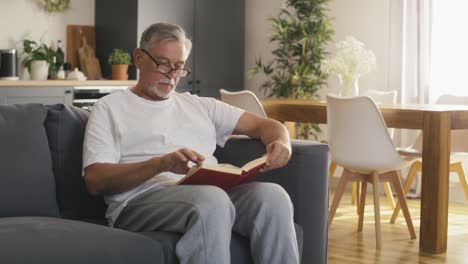 Senior-caucasian-man-reading-book-and-lying-at-the-couch.