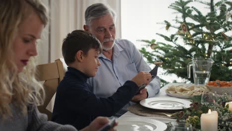 Cute-boy-showing-his-grandfather-how-to-use-mobile-phone.