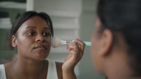 Mujer-Afroamericana-Aplicando-Colorete-De-Maquillaje-En-El-Baño.